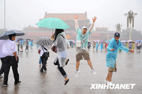 7月17日，几名来自韩国的游客在雨中的天安门广场嬉戏。